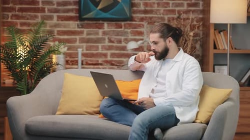 Man Working on Laptop While Sitting on Couch