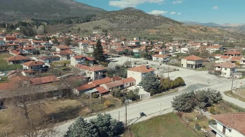 Drone orbit flight, above a village in Europe, green hills, red roof tops, little houses, sunny weat