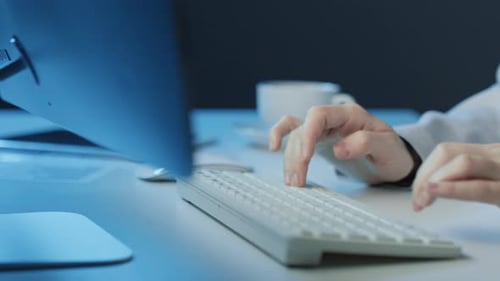 Frau sitzt am Schreibtisch und tippt auf der Tastatur