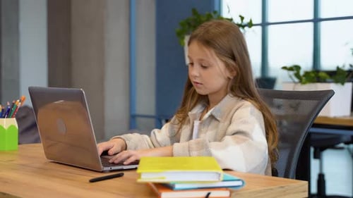 Student Girl Doing Her Homework Using Laptop in Primary School