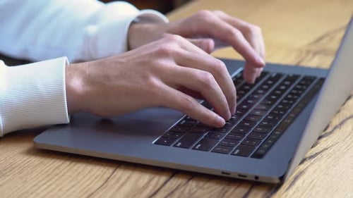 Man typing on laptop keyboard at home office workplace for online work