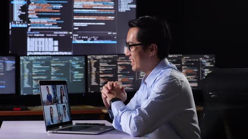 Programmeur ayant une réunion devant un ordinateur portable tout en écrivant du code sur plusieurs moniteurs affichant la base de données