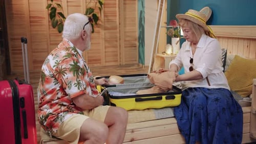 Senior Couple Packing Luggage for Tropical Vacation at Home