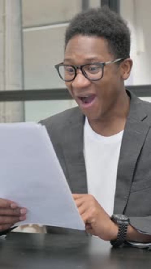 Excited Young Man Celebrates Reading Good News on Paper