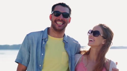 Happy hispanic couple embracing by the sea on summer vacation in slow motion