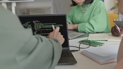Estudiantes discutiendo el Código de programación en la pantalla del portátil