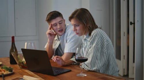 Young Adults at Table Looking at Laptop