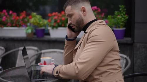 Man Talking on Cell Phone While Working on Laptop