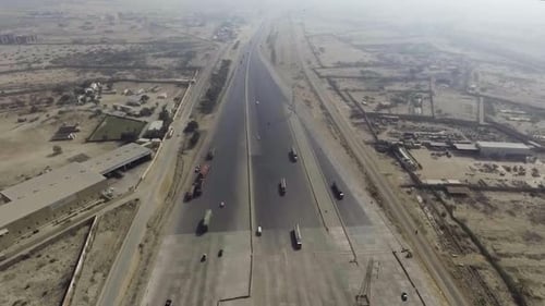 Vista superior de uma praça de pedágio na rodovia da cidade, veículos pesados e outros em movimento.