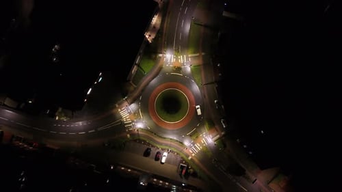 White car in illuminated roundabout at night. Small american town with glowing streetlights in quiet