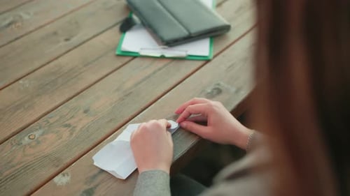 Close Up Person Folding Paper Into Kite On Wooden Table