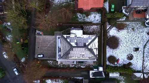 Snow-covered solar panels on roof of urban villa building. Snowy winter day in american suburb. Aeri