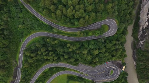 Cars Driving on Winding Mountain Road Next to River