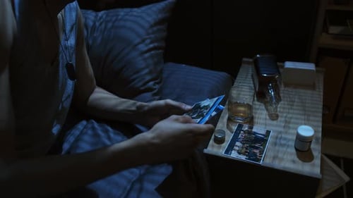 Distraught Man Reminiscing in Dark Bedroom at Night