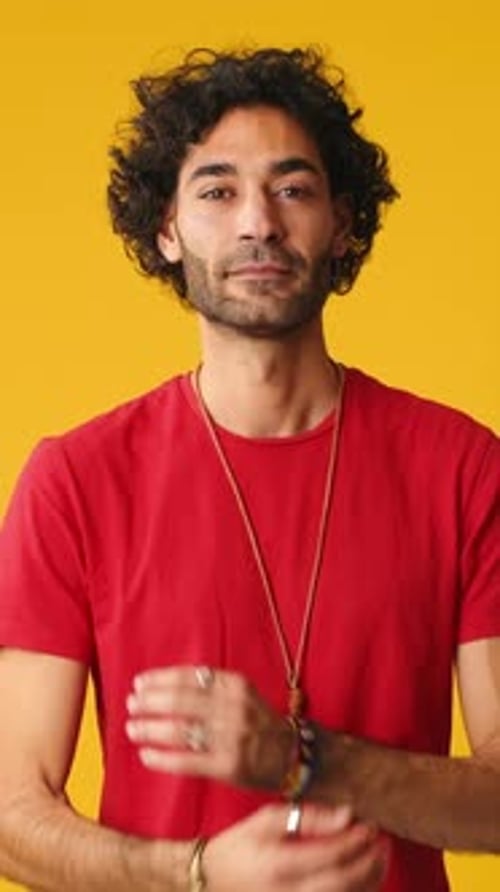 Man crossing his arms and looking at camera isolated on yellow background in studio