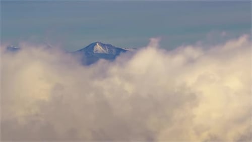 Snowy Mountains Peak Through Swirling Clouds