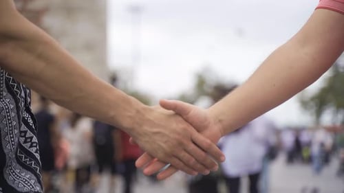 Handshake Over Blurred Crowd in Busy Urban Setting