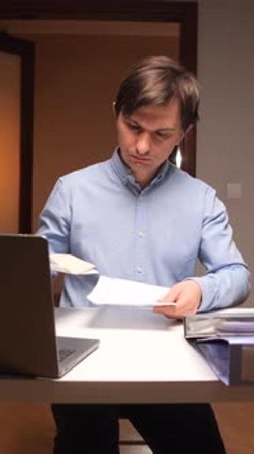 Vertical Video Office Worker Opening Envelope at Desk with Laptop and Files