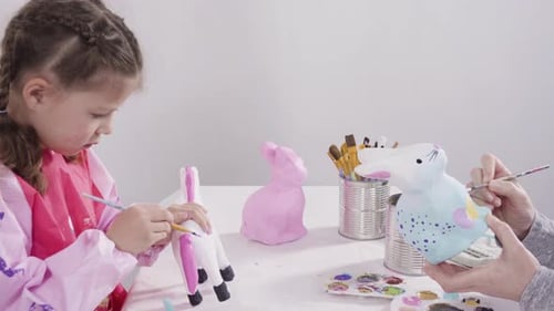 Little Girl Painting Paper Mache Figurines with Acrylic Paint for Her Homeschooling Art Project