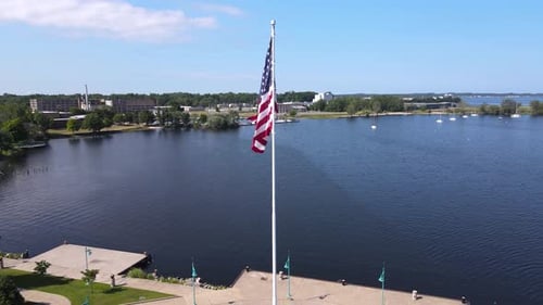 American Flag Waving over Lakeside City from Above