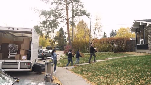 Family Moving Boxes From Moving Truck to New Home with Autumn Leaves Adult