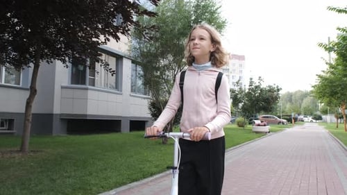 Niña monta alegremente su scooter a la escuela