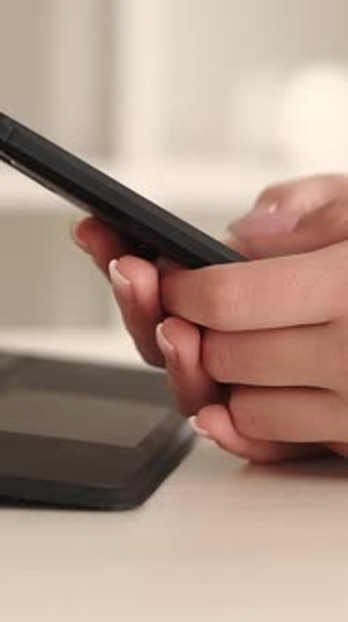 Woman Uses Cellphone Next to Tablet Device