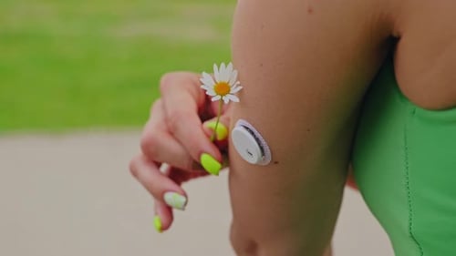 Woman with Diabetes Monitoring Device Holds Daisy