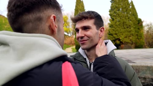 Young caucasian gay couple sharing intimate moments in a park