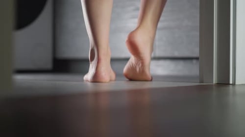 Barefoot Woman Stands in Bathroom Doorway