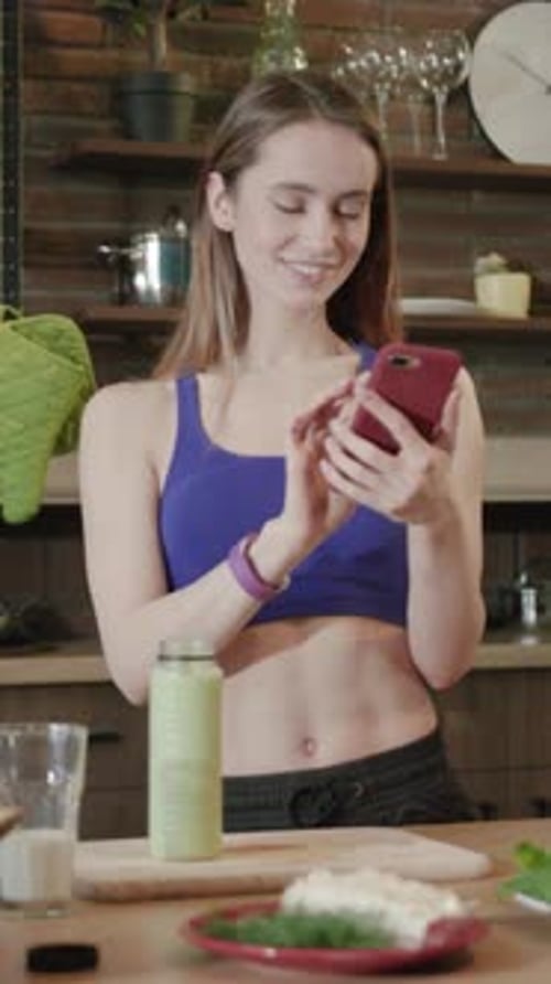 Woman Using Phone Near Smoothie in Kitchen