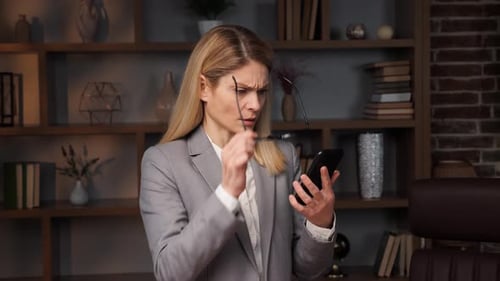 Woman in Office Looks Confused at Phone