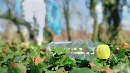 Man at plastic garbage collecting in a polluted park. Rubber gloves, taking a plastic bottle. Slow m