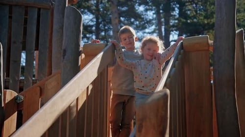 Happy Siblings Playing on Sunny Slides
