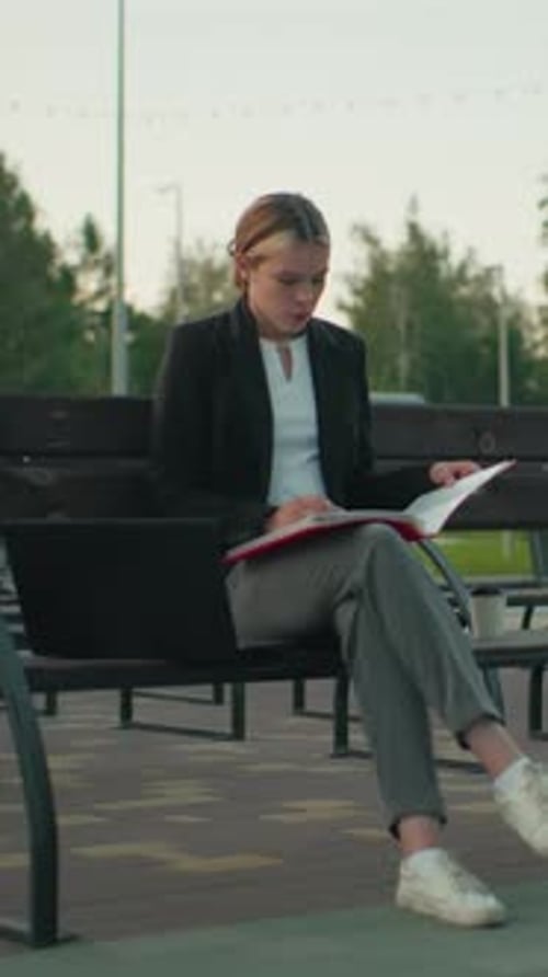 Thoughtful Woman Reviews Documents on Park Bench