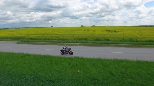 Aerial of male biker riding motorbike down a road