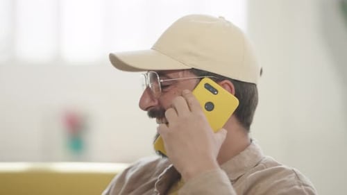 Smiling Man Chatting on a Cell Phone Indoors