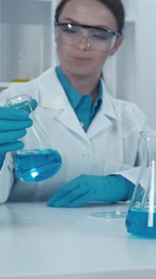Scientist Examining Blue Liquid in Laboratory Setting