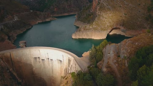 Betondamm mit Reservoirwasser in einer felsigen Schlucht
