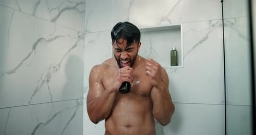 Man singing holding bottle in shower, joyful mood