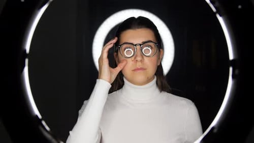 Woman Puts on Glasses in Front of Ring Light