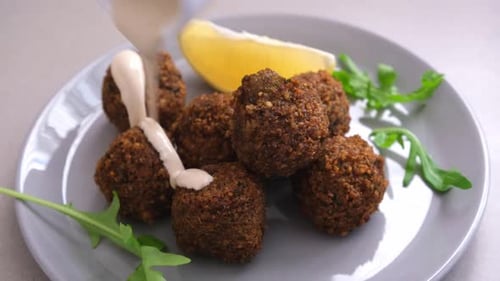 Falafel balls with tahini on gray plate.