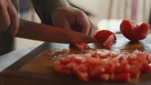Dicing fresh tomatoes on a wooden cutting board