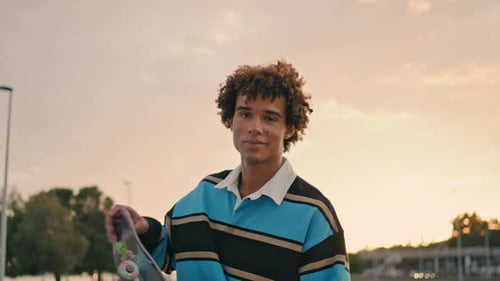 Stylish Student Holding Skate at Evening City Portrait. Young Man Looking Camera
