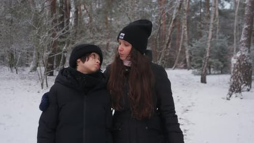 A mother comforts her sad child during a supportive walk in the snow.