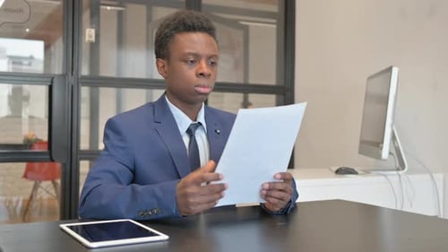 Young Professional Reviews Documents at Office Desk