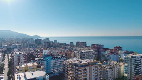 Aerial Video of a Scenic Cityscape With a Clear Blue Sky and a Sparkling Sea in the Background
