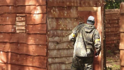 Paintball Sport Player Wearing Protective Mask Aiming Gun Shelter Under Attack