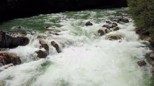 An einem strahlend sonnigen Frühlingstag fließt eine Flussströmung durch das Tal rund um die glatten Felsen