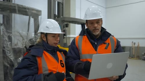 Engineers Check Plan of Inspection on Laptop in Warehouse